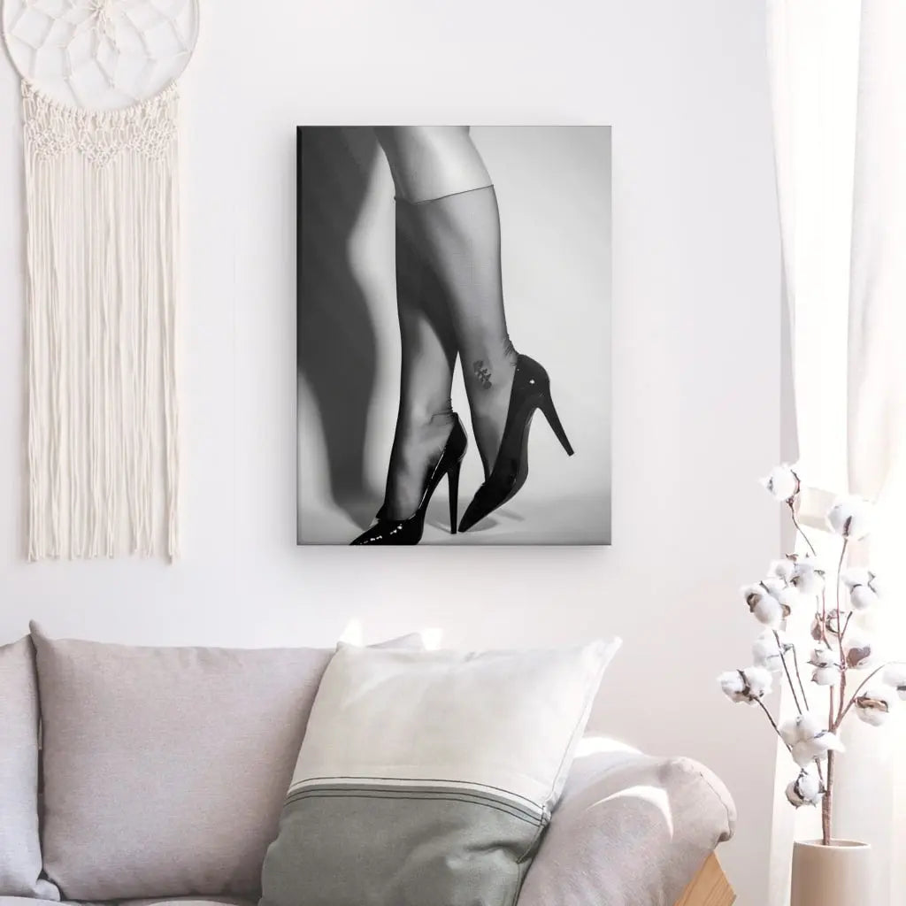 Un tableau photo monochrome d'une œuvre d'art encadrée affichant Tableau Résille Jambes Femme Escarpins Noir et Blanc, accroché sur un mur blanc au-dessus d'un canapé dans un élégant salon moderne.