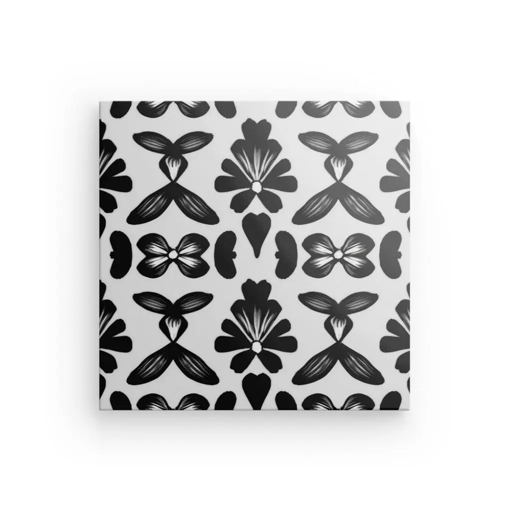 Une toile carrée présente un motif symétrique de motifs floraux noirs sur fond blanc, parfait pour ajouter une touche élégante à votre décoration intérieure avec son saisissant Tableau Motifs Ethniques Noir et Blanc.