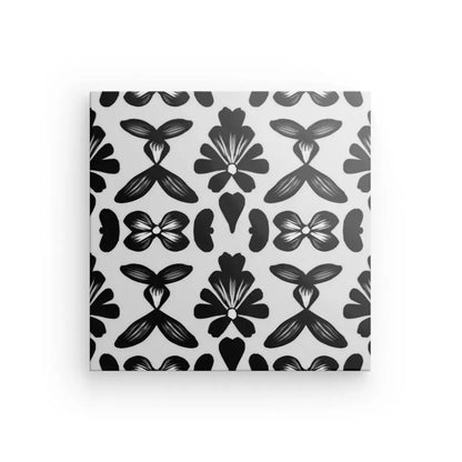 Une toile carrée présente un motif symétrique de motifs floraux noirs sur fond blanc, parfait pour ajouter une touche élégante à votre décoration intérieure avec son saisissant Tableau Motifs Ethniques Noir et Blanc.