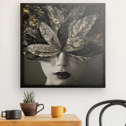 Le Tableau Visage Femme Plumes Dorées Noir et Blanc est accroché au mur au-dessus d'une table en bois avec deux mugs, une petite plante et une chaise noire - parfait pour toute décoration contemporaine.