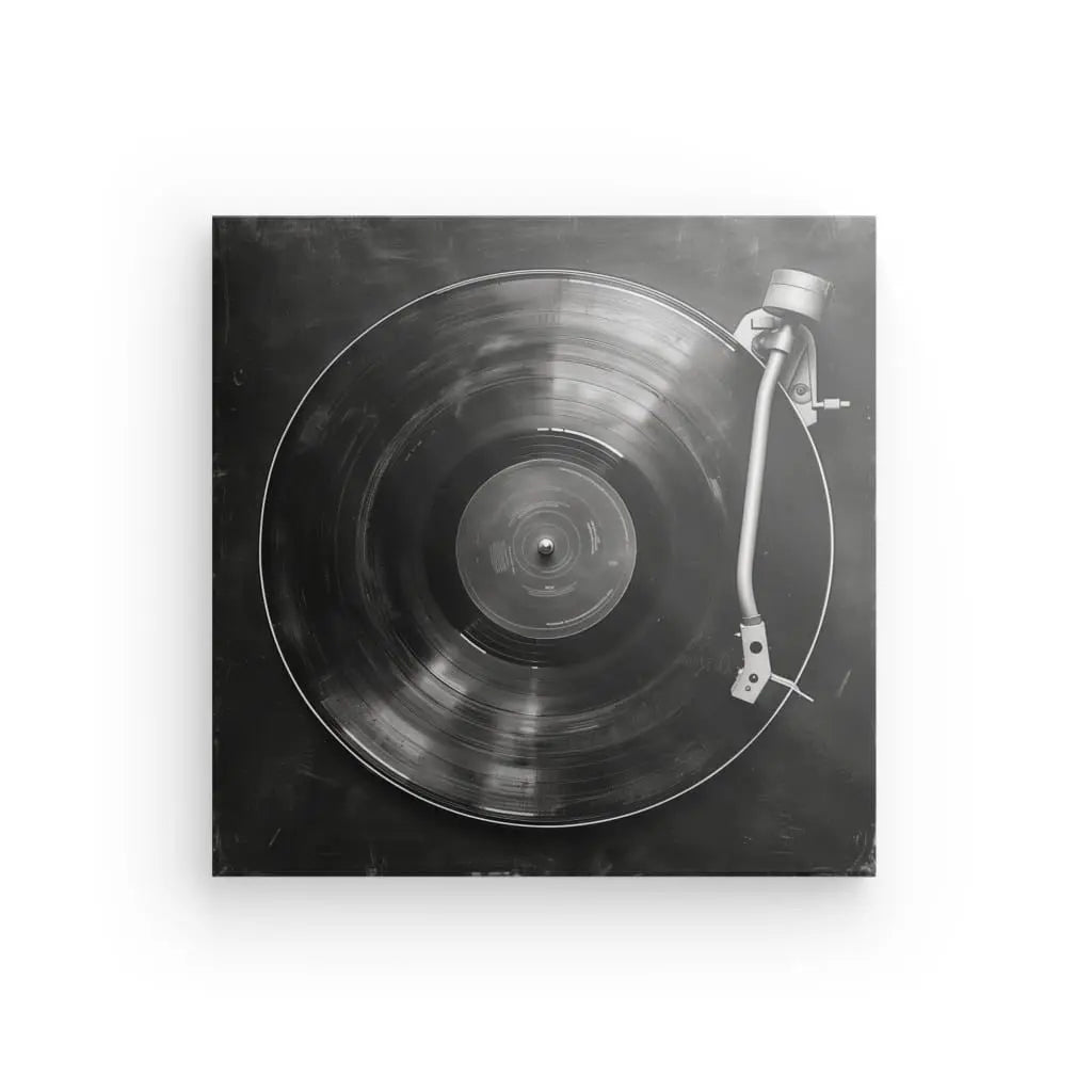 Image en noir et blanc d’un disque vinyle sur un plateau tournant, vu du dessus. Le bras du plateau tournant est positionné au-dessus du disque, évoquant un style art minimaliste parfait pour la décoration intérieure : le Tableau Platine Vinyle Minimaliste Noir et Blanc.