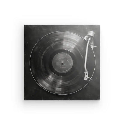 Image en noir et blanc d’un disque vinyle sur un plateau tournant, vu du dessus. Le bras du plateau tournant est positionné au-dessus du disque, évoquant un style art minimaliste parfait pour la décoration intérieure : le Tableau Platine Vinyle Minimaliste Noir et Blanc.