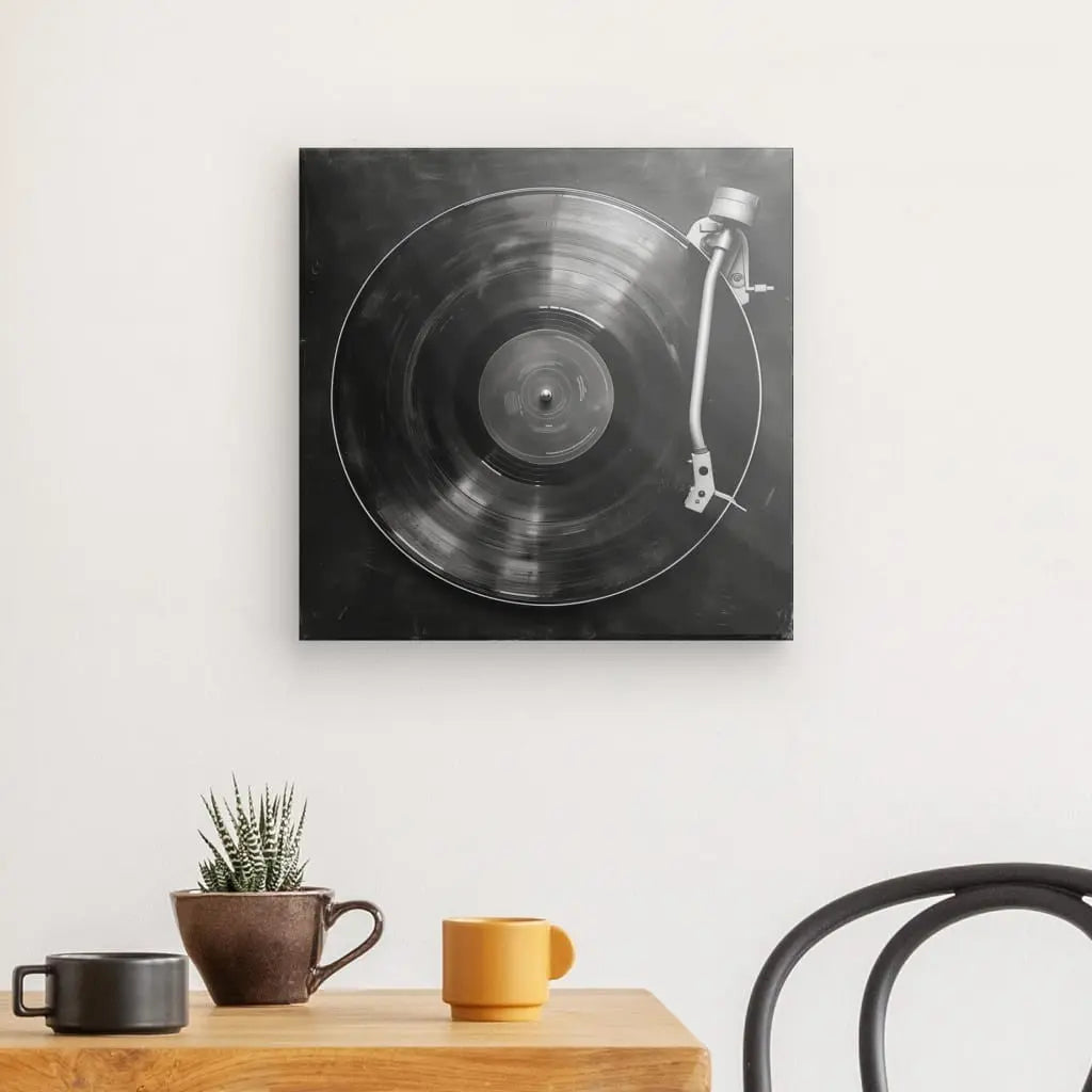 Un Tableau Platine Vinyle Minimaliste Noir et Blanc est suspendu au-dessus d'une table en bois avec deux tasses et une petite plante en pot. Une chaise noire est partiellement visible, le tout encapsulant parfaitement l'art minimaliste dans la décoration intérieure.