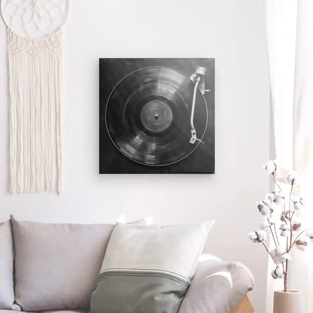 Une chambre confortable dispose d'un canapé gris clair avec des oreillers blancs et gris. Au-dessus du canapé, un Tableau Platine Vinyle Minimaliste Noir et Blanc est accroché au mur. Une tenture murale décorative et un cotonnier ajoutent à la charmante décoration intérieure.