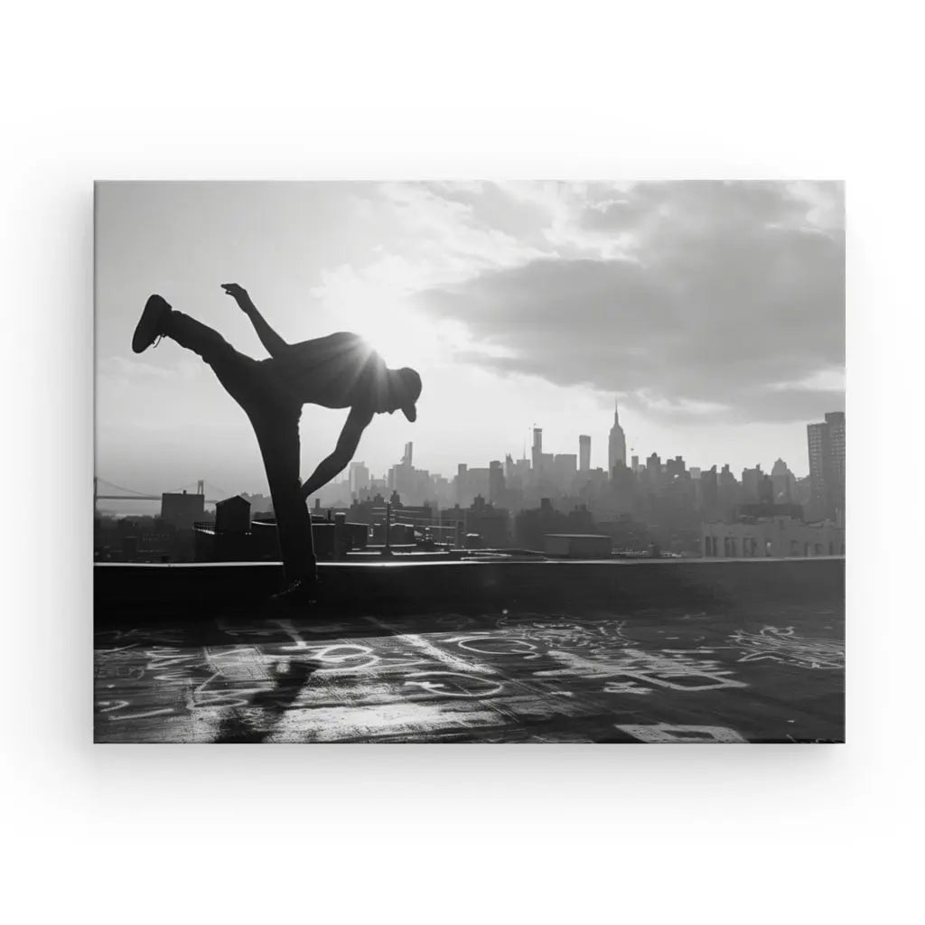 Tableau Breakdance Street Workout Noir et Blanc représente une personne exécutant un mouvement de danse sur un toit, sur fond de toits de ville avec le soleil en arrière-plan, capturant parfaitement l'essence de la danse urbaine dans un cadre contemporain.