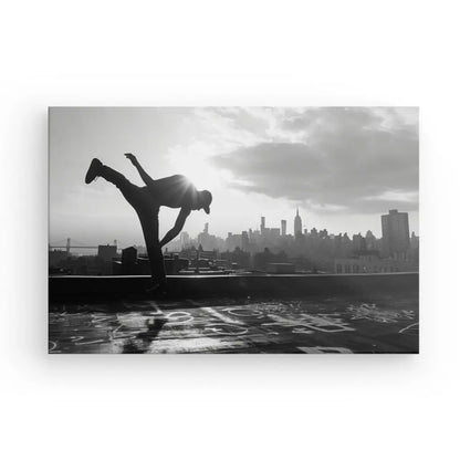 Le Tableau Breakdance Street Workout Noir et Blanc capture une personne exécutant un high kick sur un toit, avec les toits de la ville sous un ciel nuageux en arrière-plan. La scène, rappelant la danse urbaine, offre une touche exquise de décoration contemporaine à n'importe quel espace.