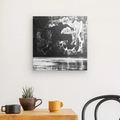 Un « Tableau Breakdance Danseur Hip-Hop Monochrome » noir et blanc est accroché sur un mur blanc au-dessus d'une table en bois ornée d'une plante en pot et de deux mugs, créant une scène rappelant l'Art Contemporain. Une chaise noire est partiellement visible à droite.