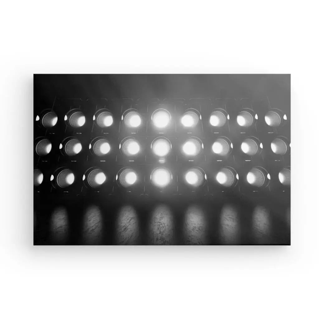 Les Tableau Projecteurs Lumineux Noir et Blanc émettent une grille lumineuse et alignée de lumières de scène circulaires, créant un tableau monochrome sur un fond sombre.