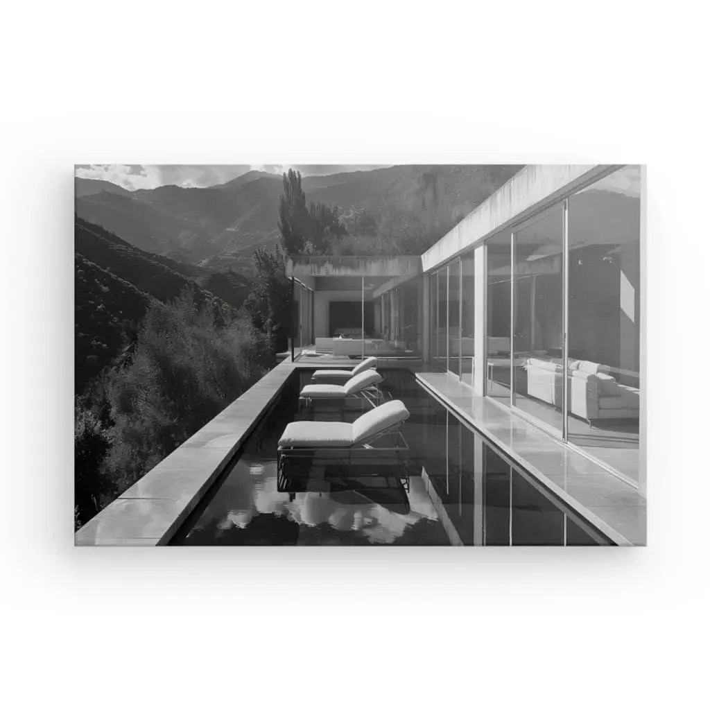 Une maison moderne avec de grandes fenêtres et une étroite piscine extérieure le long de son bord, dotée de chaises longues, située dans un cadre montagneux. Le Tableau Villa Architecture Moderne Noir et Blanc présente l'architecture moderne élégante complétée par une décoration intérieure subtile dans une photographie en noir et blanc saisissante.