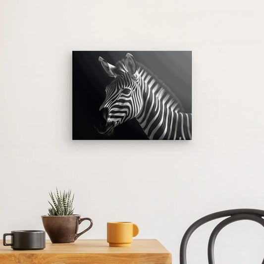 Une photo encadrée du Tableau Minimaliste Zèbre Fond Noir et Blanc est accrochée sur un mur blanc au-dessus d'une table en bois. La table contient une petite plante en pot, une tasse marron et une tasse jaune. Le tableau noir et blanc ajoute une touche élégante à la scène, avec une partie d'une chaise noire visible à droite.