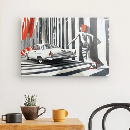 Le tableau dessin moderne noir blanc rouge accroché au mur représente une femme en robe rayée passant devant une voiture blanche d'époque, sur fond de rayures verticales noires et blanches. Au premier plan, une table accueille une plante et deux mugs.