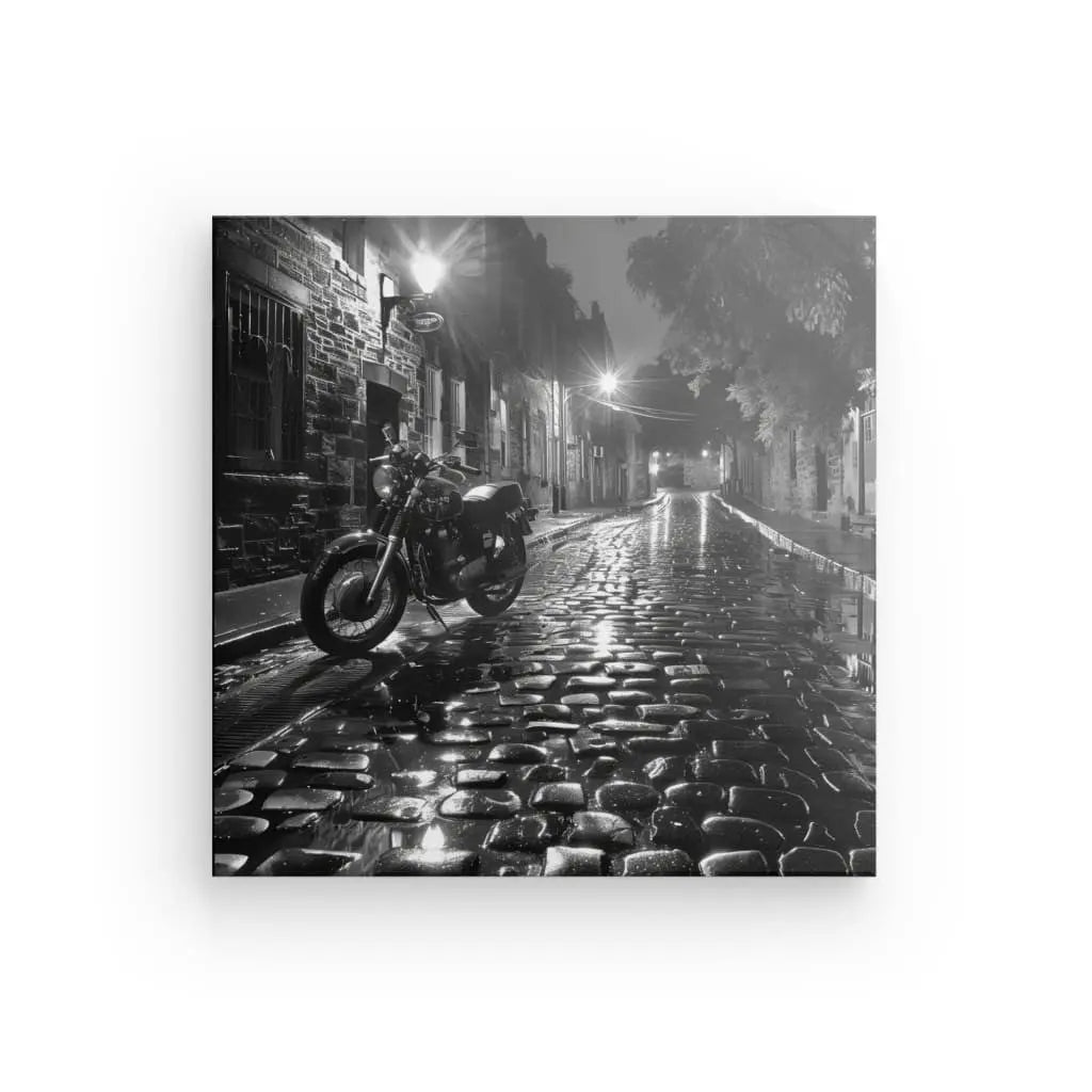 Motorcycle on wet cobblestone street at night, black and white.