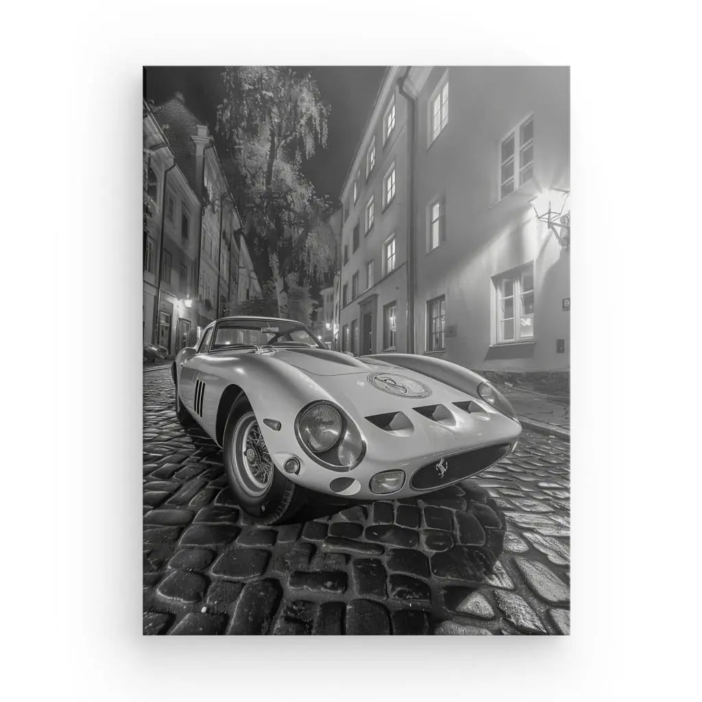 Le « Tableau Ford GT Ruelle Pavée Monochrome » présente une voiture de sport Ferrari classique garée sur une rue pavée avec des bâtiments historiques et des arbres en arrière-plan, capturée en noir et blanc sur une toile blanche brillante à texture fine.