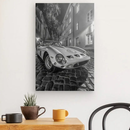 Le Tableau Ford GT Ruelle Pavée Monochrome, capturant une voiture ancienne sur une rue pavée en noir et blanc, est accroché sur un mur blanc au-dessus d'une table en bois ornée d'une petite plante en pot et de trois tasses, mettant parfaitement en valeur son attrait classique de design polyvalent.