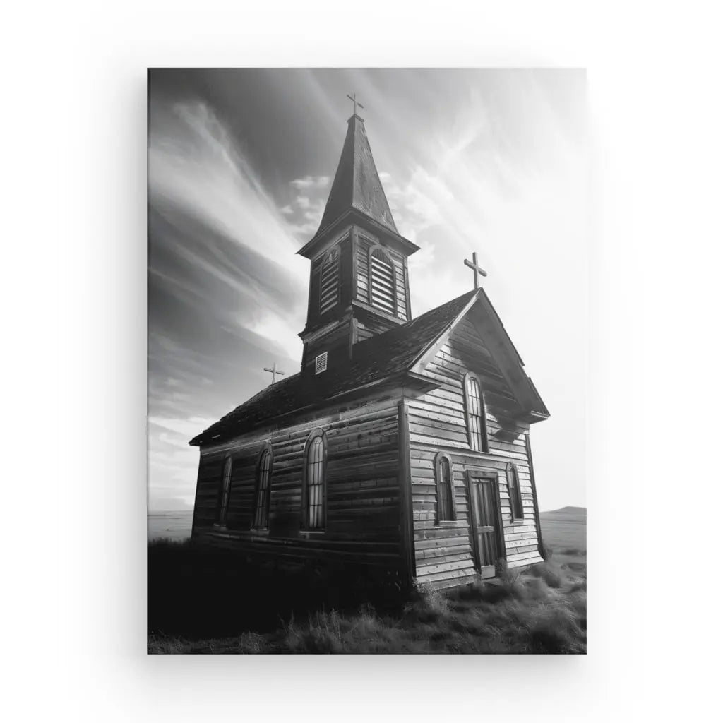 Tableau Eglise en Bois Noir et Blanc : Une toile tendue à la main avec une photographie en noir et blanc d'une vieille église en bois avec un haut clocher, sur fond de ciel dramatique avec des nuages vaporeux. L'église patinée par les intempéries est située dans un paysage herbeux et magnifiquement capturée à l'aide d'encres HP Latex.