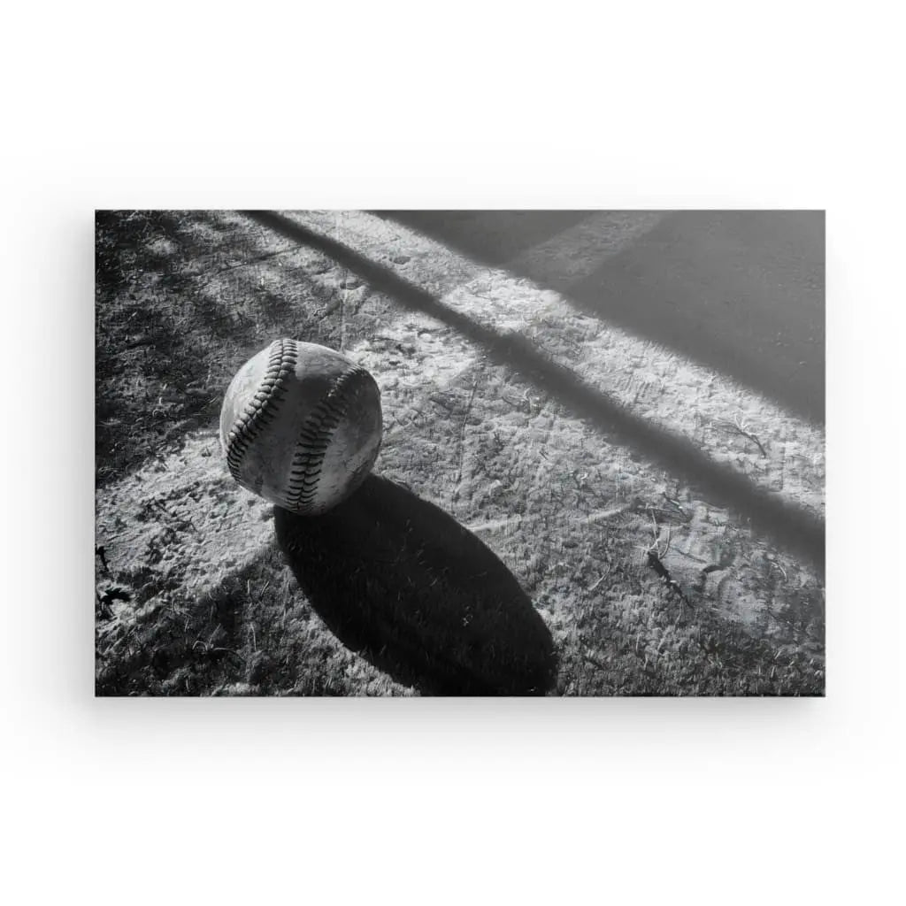 Tableau Balle Baseball Terrain Noir et Blanc présentant une photo en noir et blanc d'une balle de baseball posée au sol, projetant une ombre.