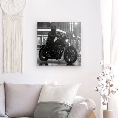 Un Tableau Moto Virée Urbaine Nocturne Monochrome est exposé sur un mur au-dessus d'un canapé clair avec coussins, à côté d'un rideau blanc et d'une tenture murale tissée.