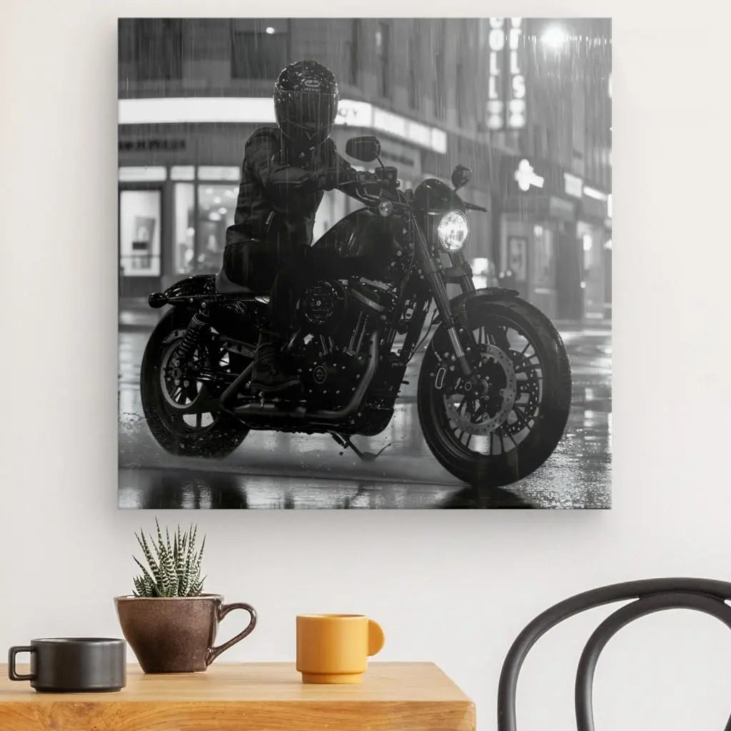 Photographie en noir et blanc d'un motocycliste sous la pluie, intitulée « Tableau Moto Virée Urbaine Nocturne Monochrome », imprimée avec des encres HP Latex, affichée sur un mur au-dessus d'une petite table avec une plante en pot et deux tasses.