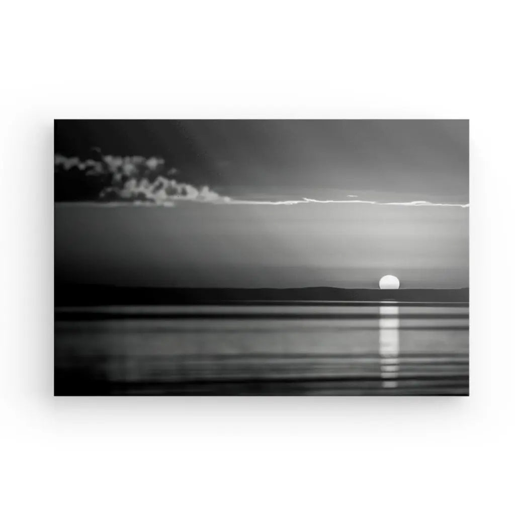 Le Tableau Coucher de Soleil Mer Noir et Blanc présente des reproductions photographiques en noir et blanc d'un coucher de soleil serein sur l'océan, avec le soleil partiellement visible à l'horizon et reflété sur l'eau. De fins nuages s'étendent dans le ciel au-dessus. Cette pièce étirée à la main utilise des encres HP Latex pour garantir une beauté durable.