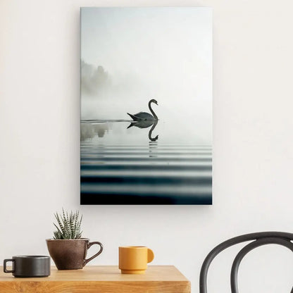 Un Tableau Cygne Lac Style Epuré représentant un cygne nageant dans de l'eau brumeuse est accroché au mur au-dessus d'une table en bois avec deux tasses et une petite plante en pot, créant un décor moderne dans une pièce par ailleurs minimaliste.