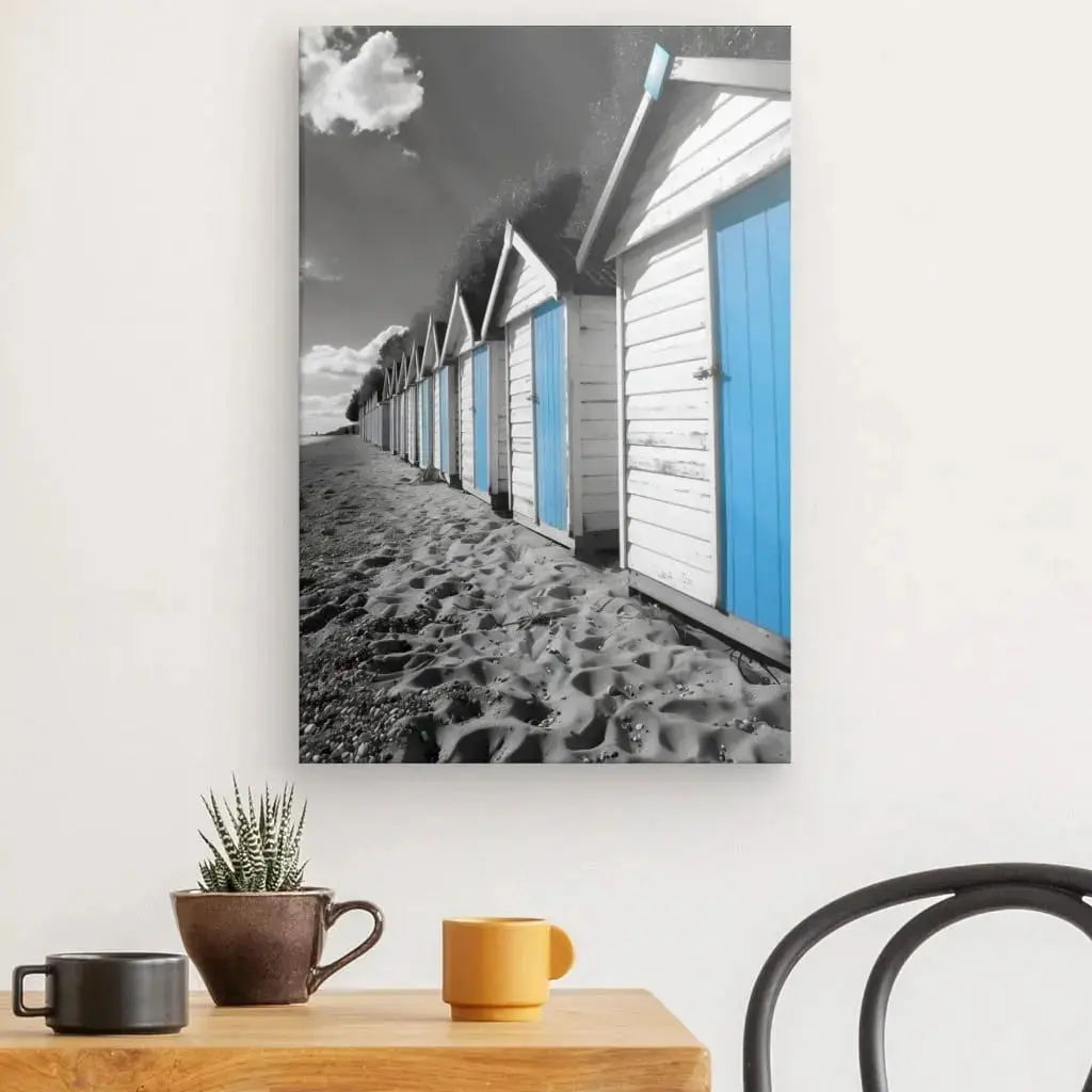 Tableau de cabanes de plage en noir et blanc avec des touches de bleu, scène côtière vive et contrastée