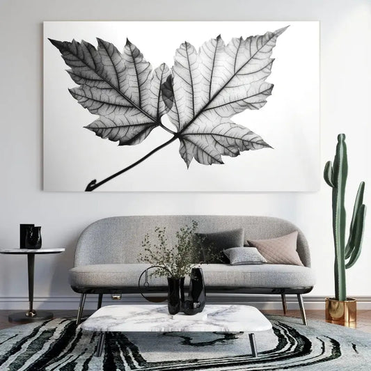 Tableau noir et blanc représentant une feuille d’arbre parmi des végétaux, scène naturelle au style épuré et élégant