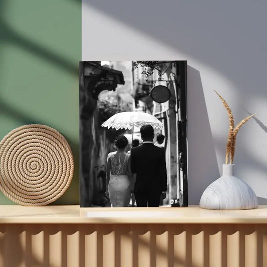 Tableau noir et blanc de mariés vus de dos sous une ombrelle, scène romantique et élégante