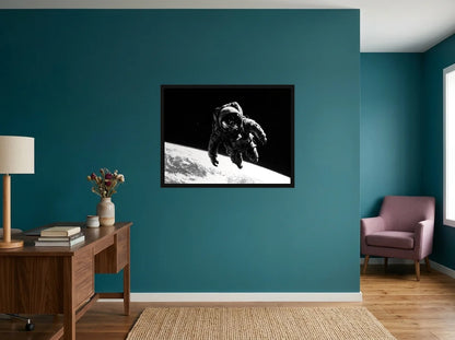 Tableau astronaute visière lunaire noir et blanc en toile encadrée noire, présenté dans : bureau aux murs bleu canard