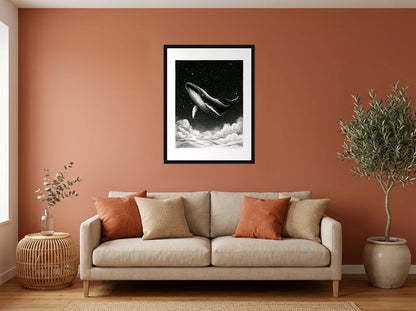 Tableau baleine au-dessus des nuages noir et blanc en toile encadrée noire, présenté dans : salon aux murs terracotta