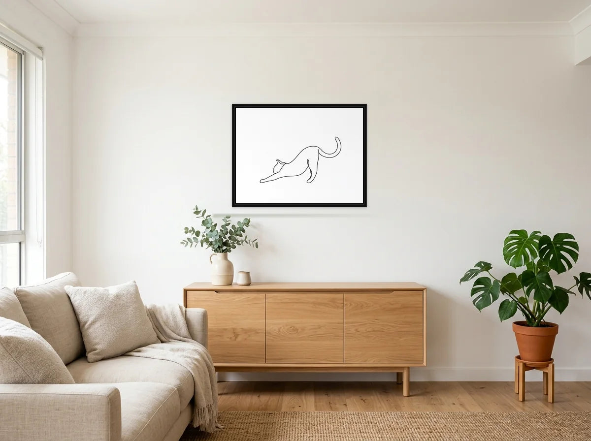 Tableau chat qui s’étire noir et blanc en toile encadrée noire, présenté dans salon blanc chaleureux et bois clair