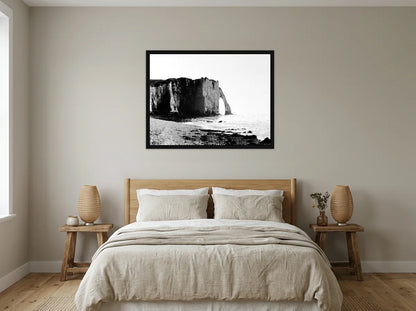 Tableau falaises d’étretat noir et blanc en toile encadrée noire, présenté dans chambre aux tons lin et grège