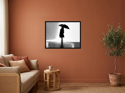 Tableau Femme au Parapluie noir et blanc en toile encadrée noire, présenté dans un salon aux murs terracotta