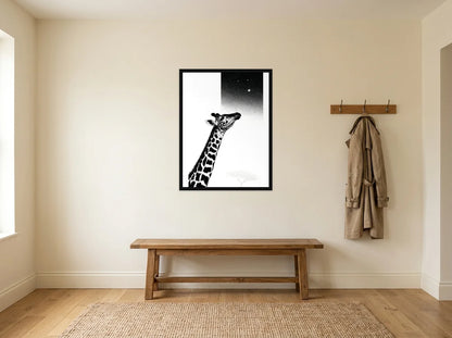 Tableau girafe sous les étoiles noir et blanc en toile encadrée noire, présenté dans une entrée crème avec banc en bois