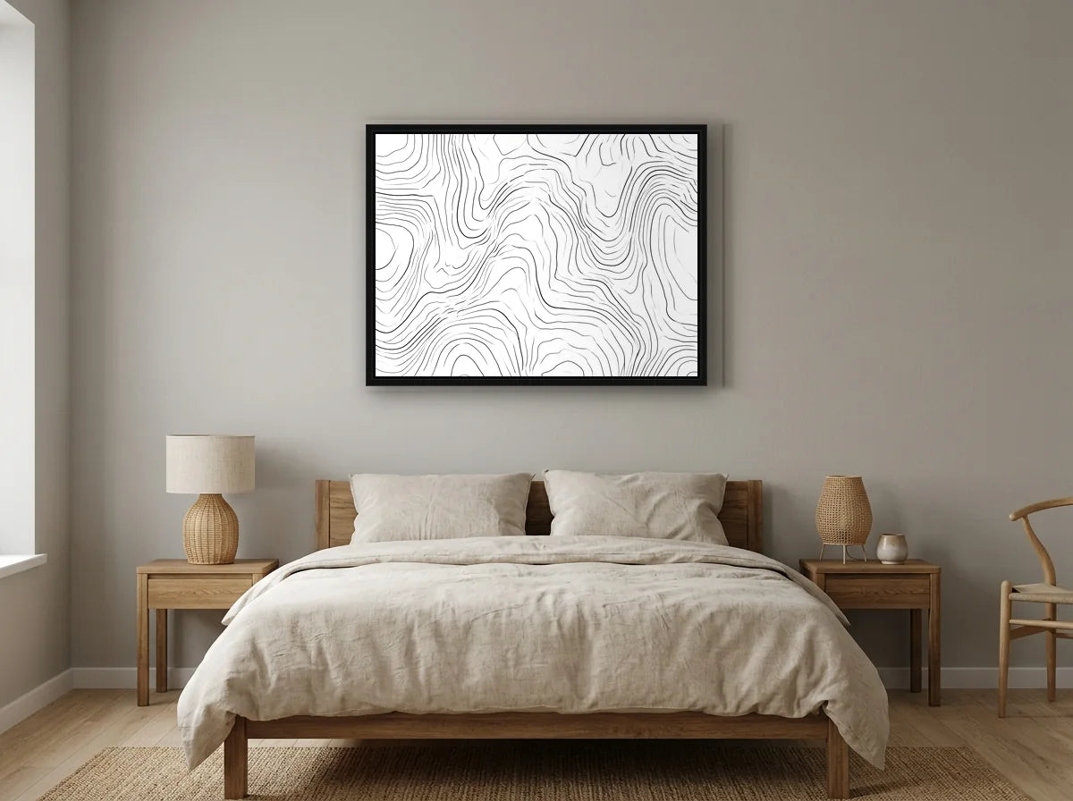 Tableau lignes topographiques abstraites noir et blanc en toile encadrée noire, présenté dans un intérieur chaleureux