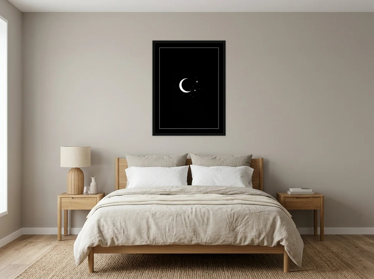 Tableau lune et étoiles noir et blanc en toile encadrée noire, présenté dans une chambre aux tons lin et grège