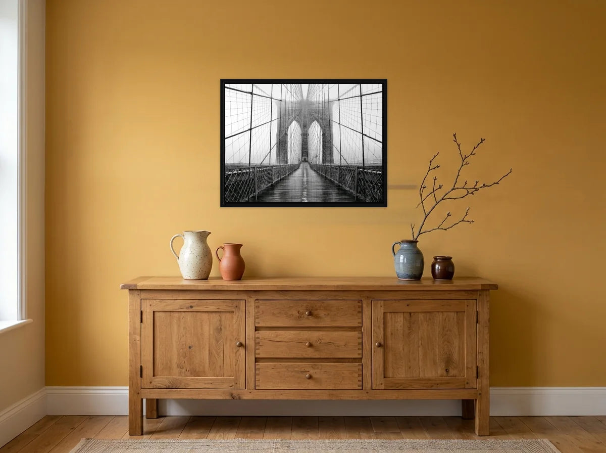 Tableau passerelle du pont de Brooklyn noir et blanc en toile encadrée noire, présenté dans une salle à manger aux murs ocre