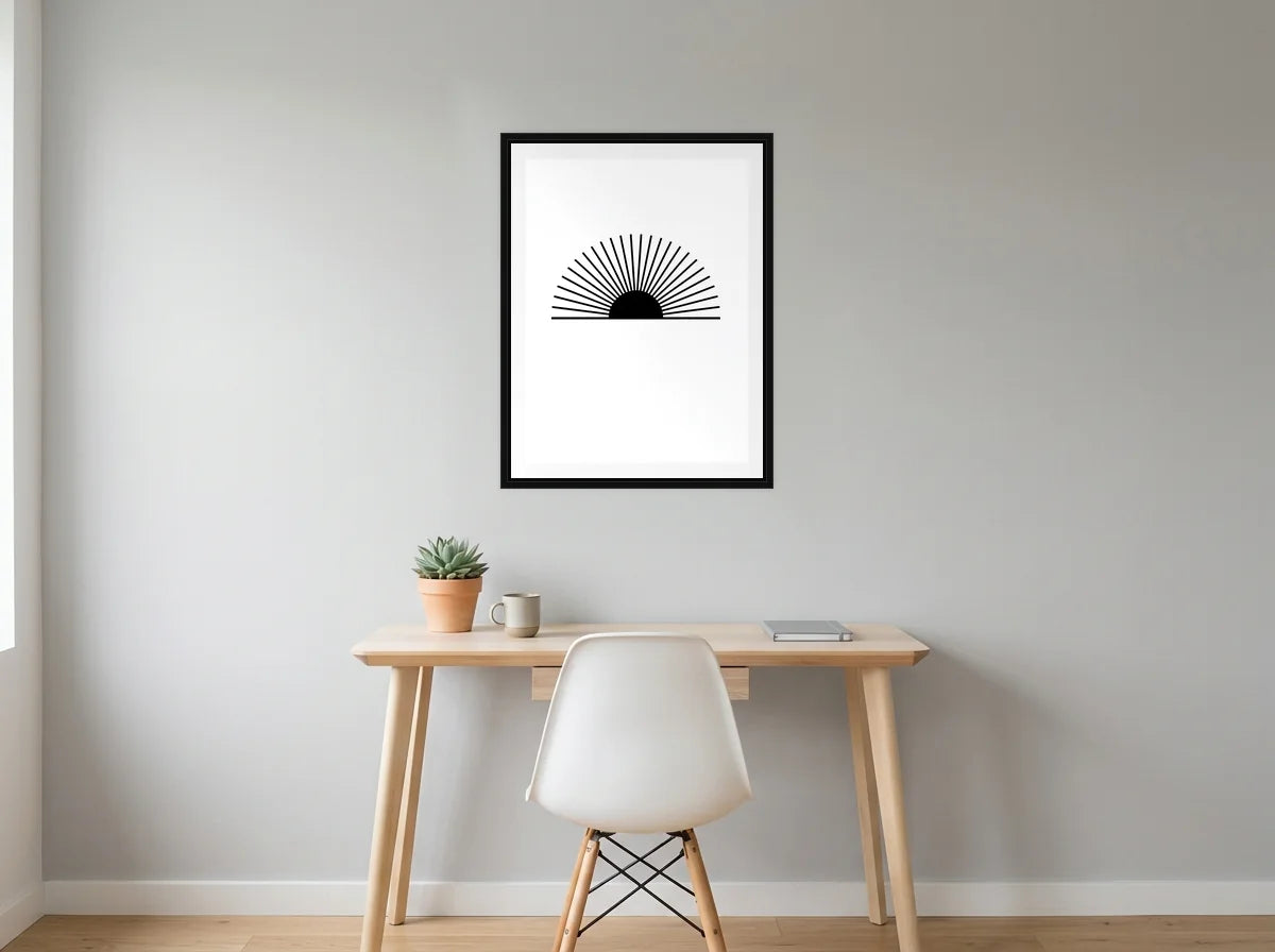 Tableau soleil levant rayonnant noir et blanc en toile encadrée noire, mis en scène dans : bureau gris clair lumineux