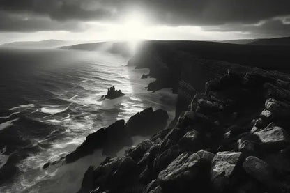 Image en noir et blanc d'un littoral accidenté en Bretagne, avec des vagues s'écrasant contre les falaises. Le soleil brille à travers les nuages, projetant lumière et ombres sur le Tableau Paysage Maritime Bretagne Falaises Noir et Blanc.