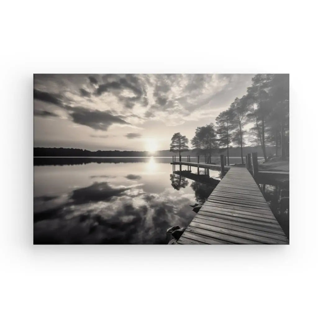 Une photo du Tableau Ponton Lac Nature Noir et Blanc montre un lac tranquille avec un ponton dans un lac s'étendant vers l'eau, entouré de grands arbres sous un ciel nuageux et ensoleillé avec des reflets à la surface de l'eau.