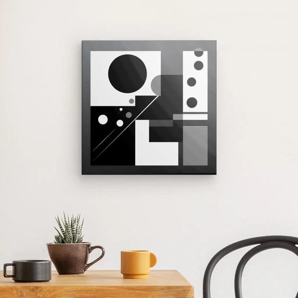 Un tableau en noir et blanc Tableau Formes Géométriques Noir et Blanc Art Abstrait Décoration Minimaliste Cercles est accroché sur un mur au-dessus d'une table en bois avec une petite plante en pot et trois tasses (marron, jaune et gris). Une chaise partiellement noire est visible à droite, rehaussant la déco intérieure minimaliste.