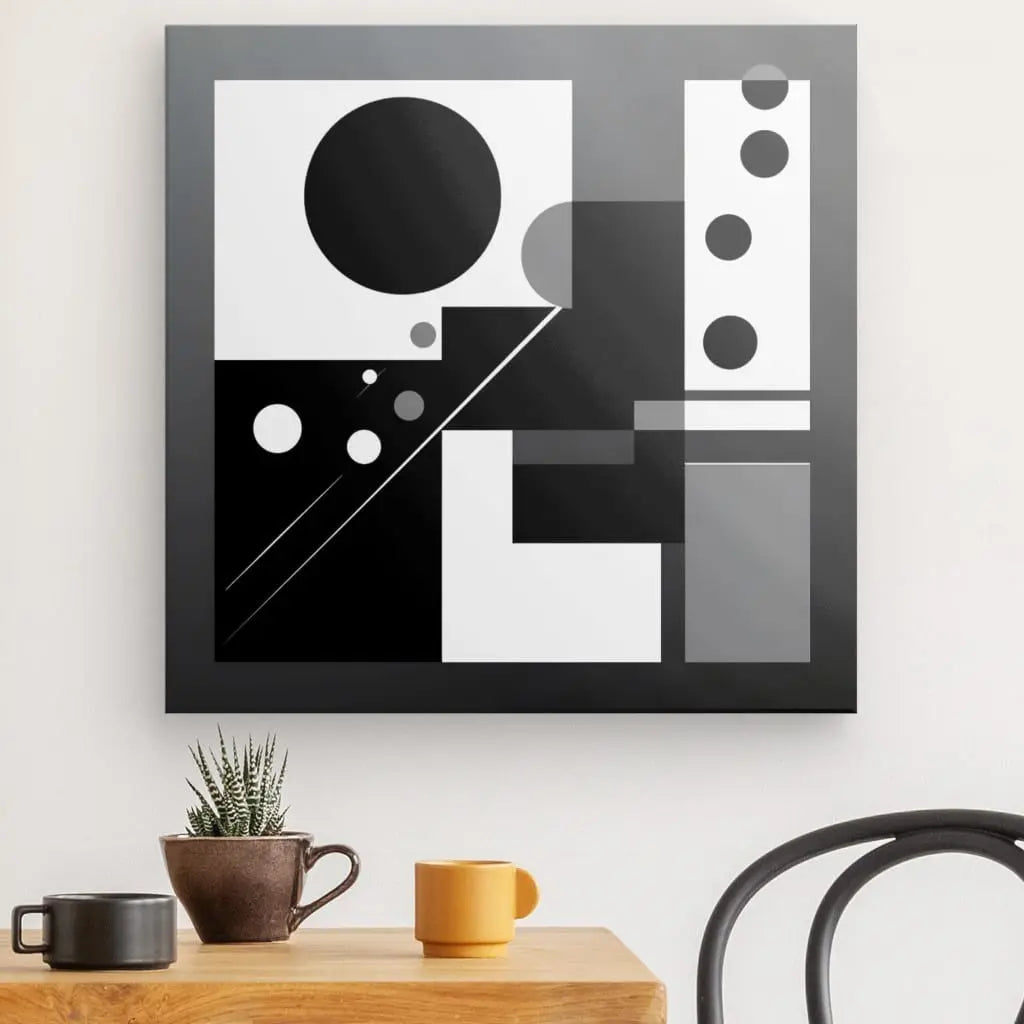 Un Tableau Formes Géométriques Noir et Blanc Art Abstrait Décoration Minimaliste Cercles orne le mur de couleur claire au-dessus d'une table en bois avec une petite plante en pot, une tasse orange et une tasse jaune. L'art géométrique noir et blanc ajoute à la déco intérieure minimaliste, tandis qu'une chaise partielle est visible à droite.