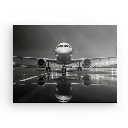 Tableau Avion Jet Photographie Nocturne Noir et Blanc sur un tarmac mouillé la nuit avec des surfaces réfléchissantes, des lumières ambiantes d'aéroport et l'élégance du noir et blanc.