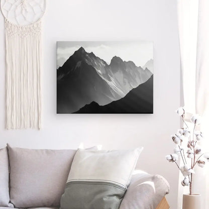 Une toile Tableau Photo Pyrénées Montagnes monochrome suspendue au-dessus d'un canapé confortable avec des coussins décoratifs dans une pièce bien éclairée.